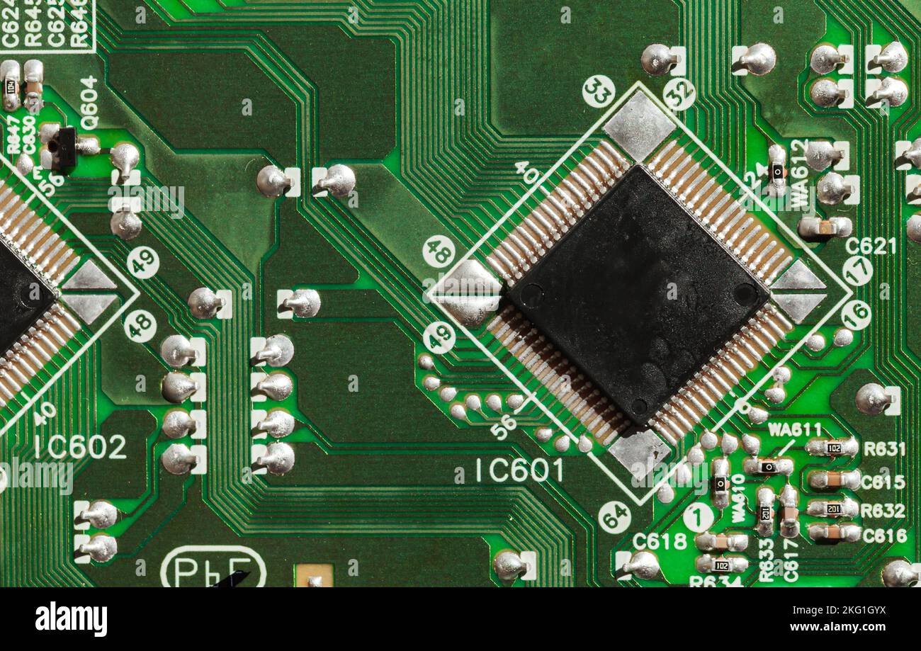 Microchip und Kondensatoren befinden sich auf einem grünen gedruckten Schaltkreis, Draufsicht, Nahaufnahme Stockfoto