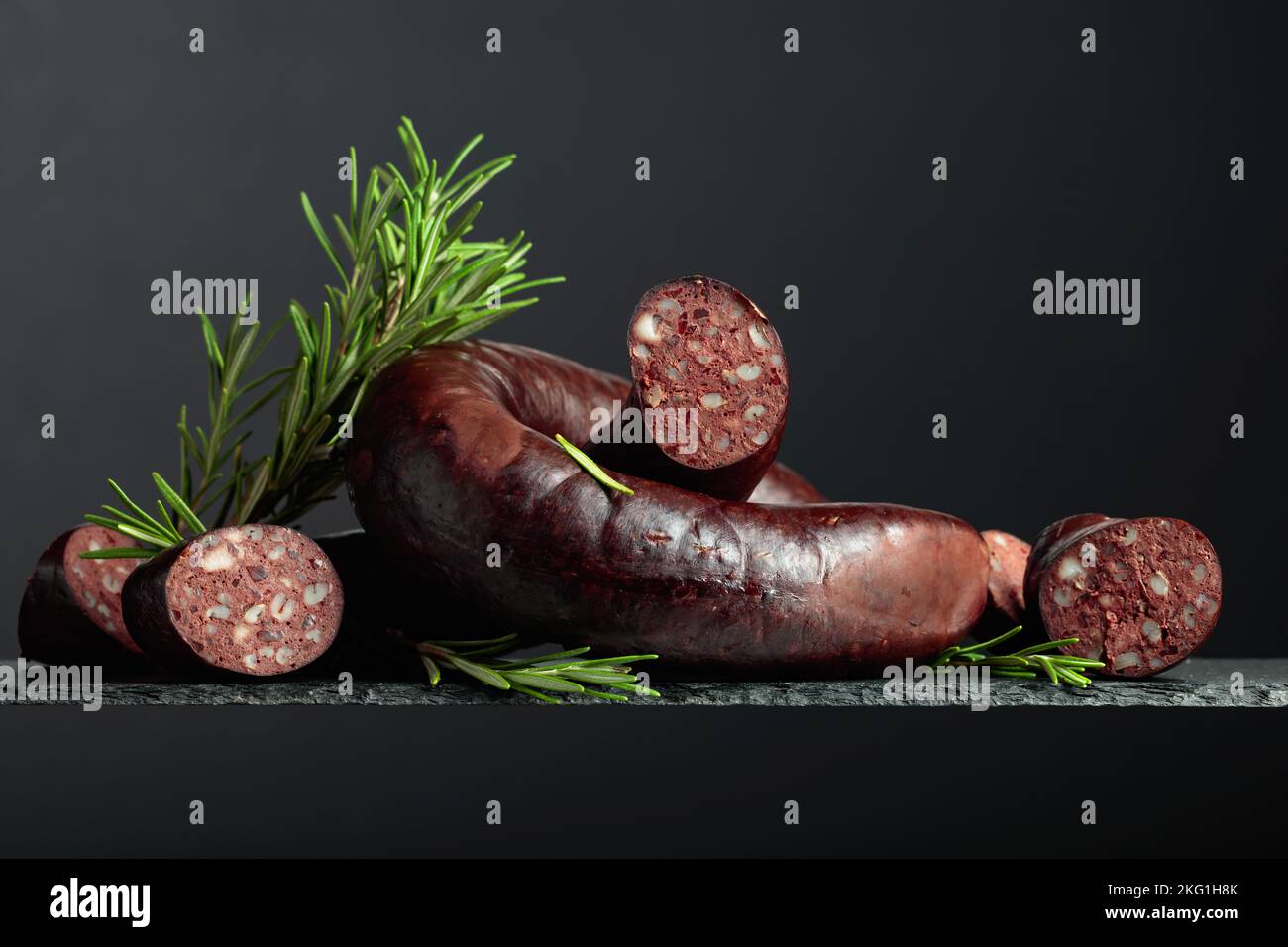 Spanischer Blutwurst oder Blutwurst mit Rosmarin auf schwarzem Hintergrund. Stockfoto