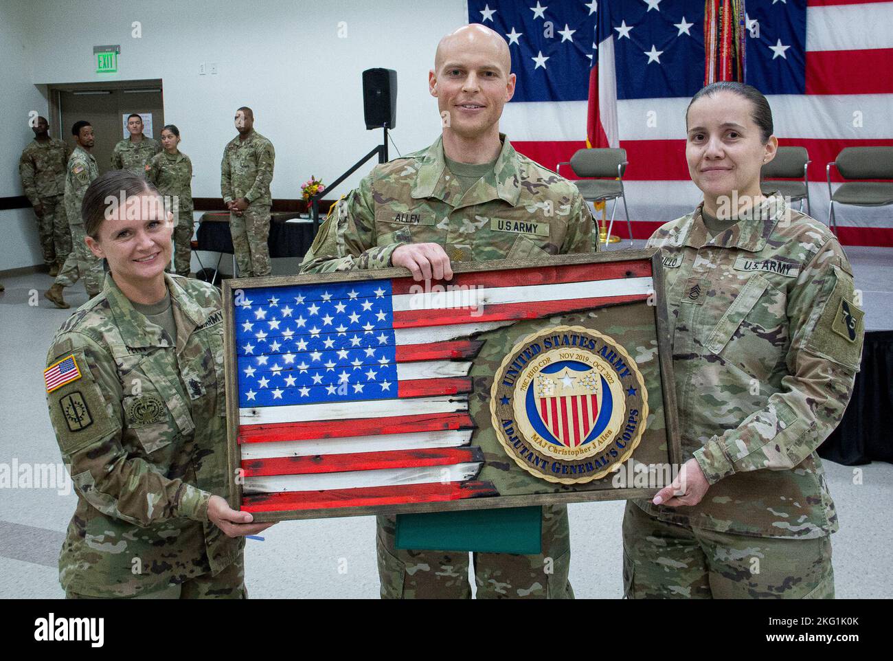 Erstes Sgt. Leesa Petty, scheidender erster Sergeant und Sgt. 1. Class Marina Carrillo, Senior Human Resources non-Commissioned Officer, Headquarters and Headquarters Detachment, 75. Innovation Command, übergibt dem scheidenden HHD-Kommandanten Maj. Christopher Allen eine benutzerdefinierte Plakette als Zeichen der Wertschätzung des Kommandos für Allens dreijährige Amtszeit. Die Holzfahne wurde von Col. Steven Waldrop, dem G3/5/7-Chef des Innovation Command von 75., von Hand gebaut. Stockfoto