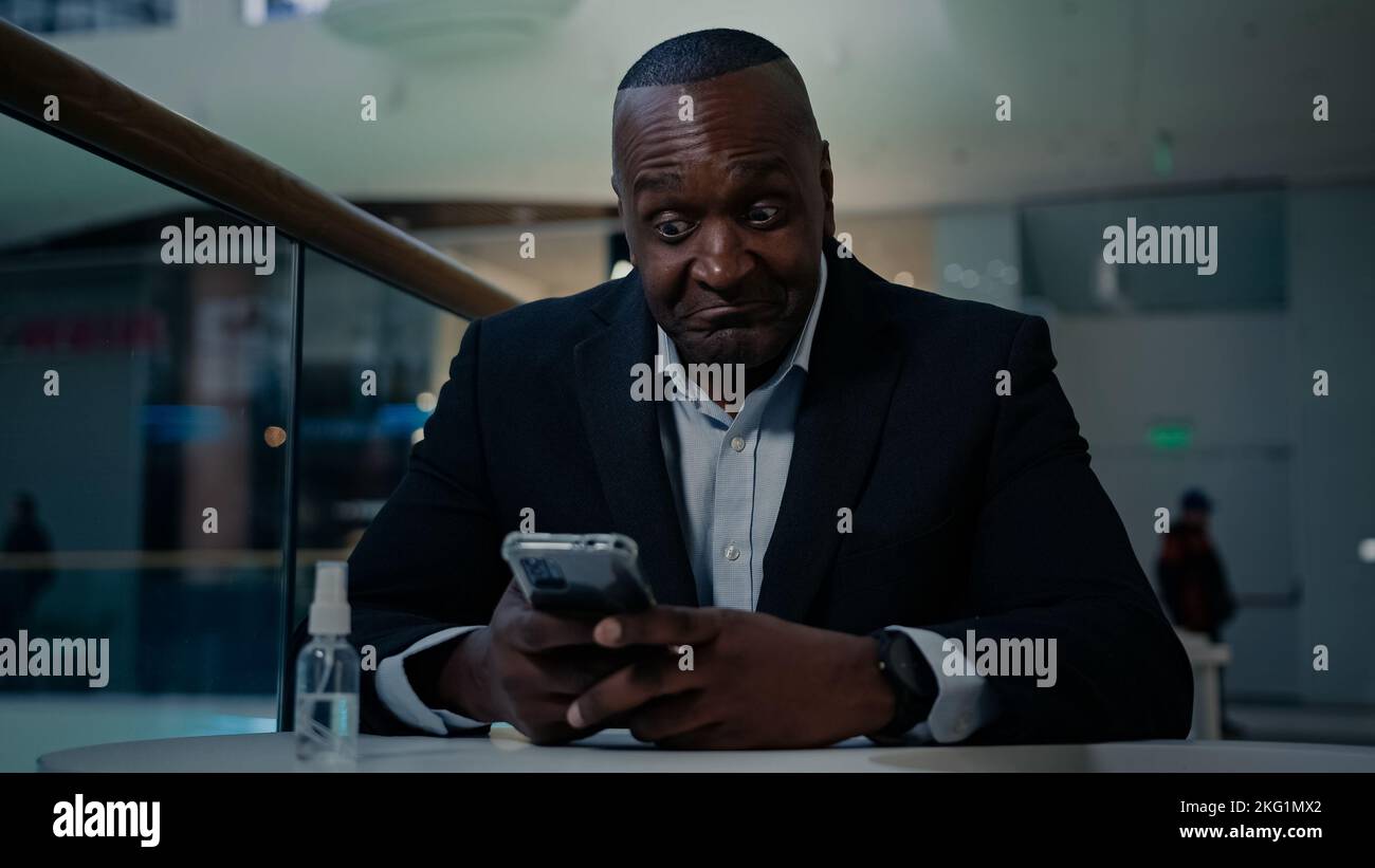 Afroamerikanische Erwachsene mittleren Alters reifen Mann Mitarbeiter Geschäftsmann drinnen im Büro Café Tisch suchen Telefon eingeben Chat SMS-SMS Stockfoto