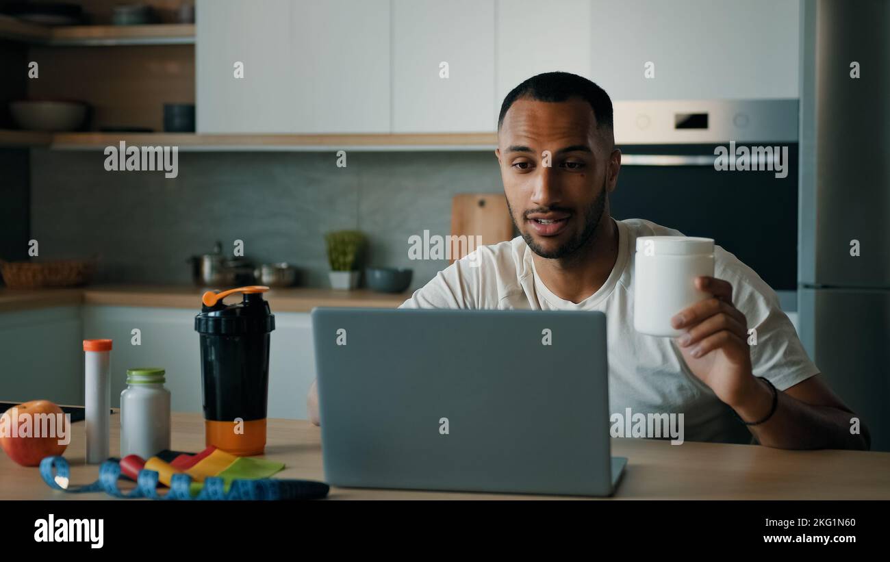 African American 30s männlich Arzt Ernährungswissenschaftler Mann Fitness-Trainer erklären Sport Ernährung Vitamin Nahrungsergänzung Protein showing jar online Video Call on Stockfoto