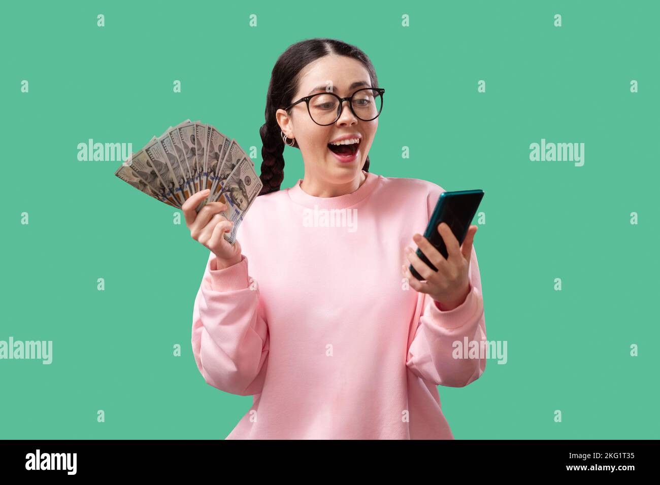 Porträt einer fröhlichen jungen Frau, die Geldscheine hält und isoliert auf gelbem Hintergrund feiert Stockfoto