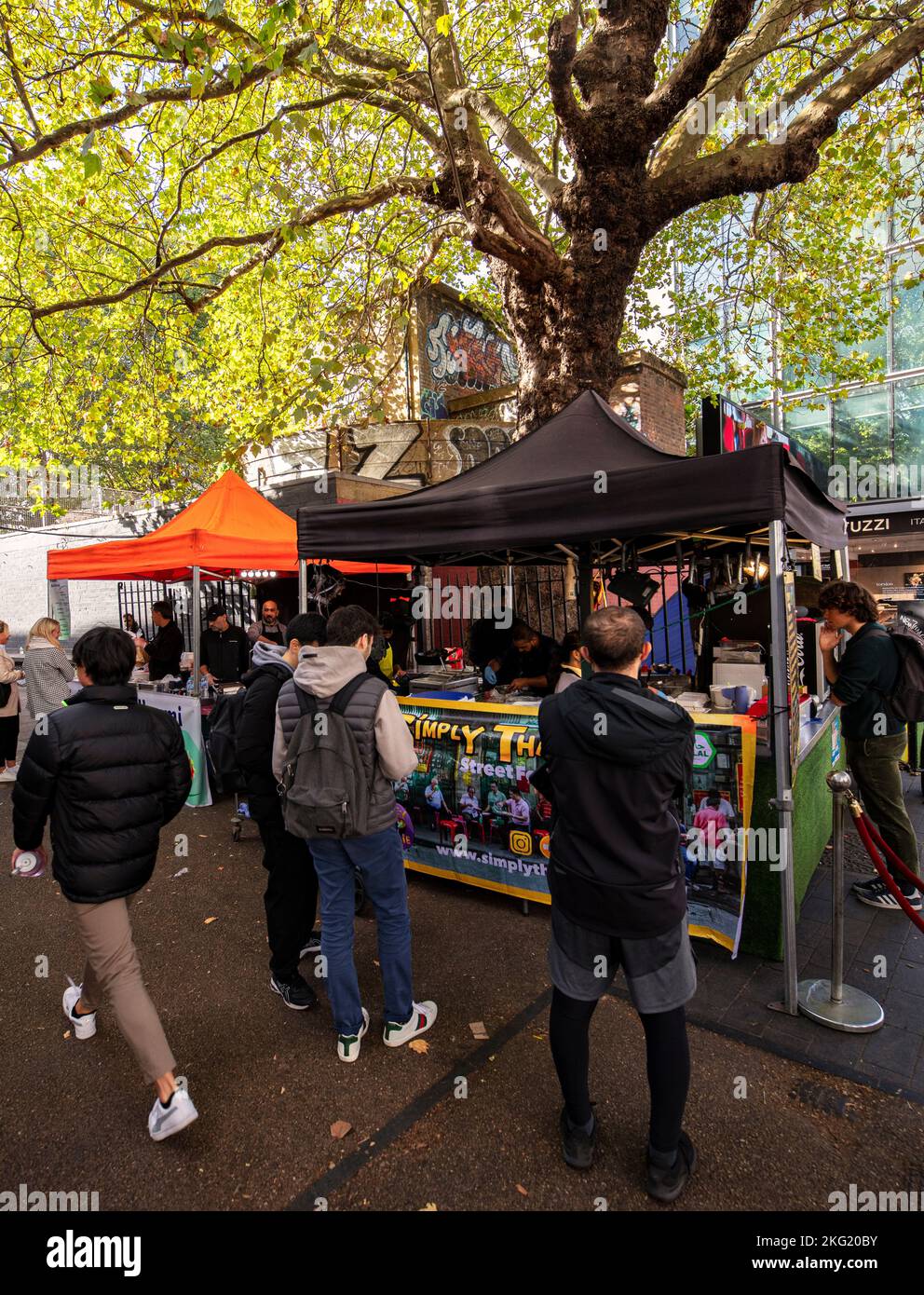 Tottenham Court Road, eine beliebte zentrale Einkaufsstraße in London, mit Verkaufsständen, an denen Lebensmittel und Touristen verkauft werden Stockfoto