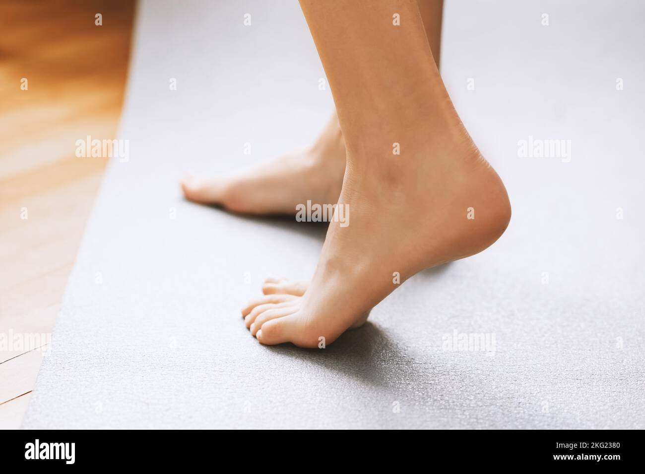 Eine Seitenansicht aus der Nähe von einer nicht erkennbaren Frau, die barfuß auf einem warmen, beheizten Holzboden stand Stockfoto