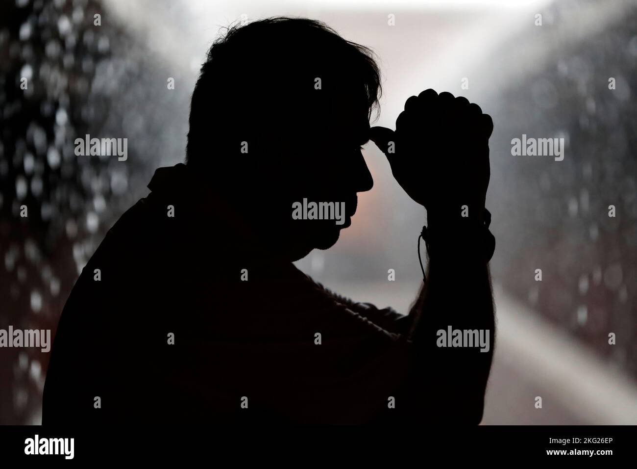 Schwarz-weiße Silhouette eines Mannes, der während der Regenzeit betet. Stockfoto