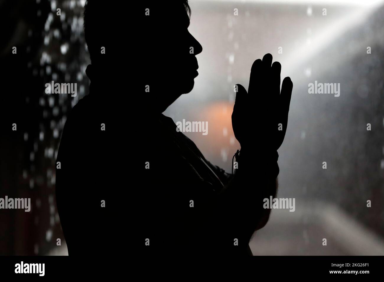 Schwarz-weiße Silhouette eines Mannes, der während der Regenzeit betet. Stockfoto