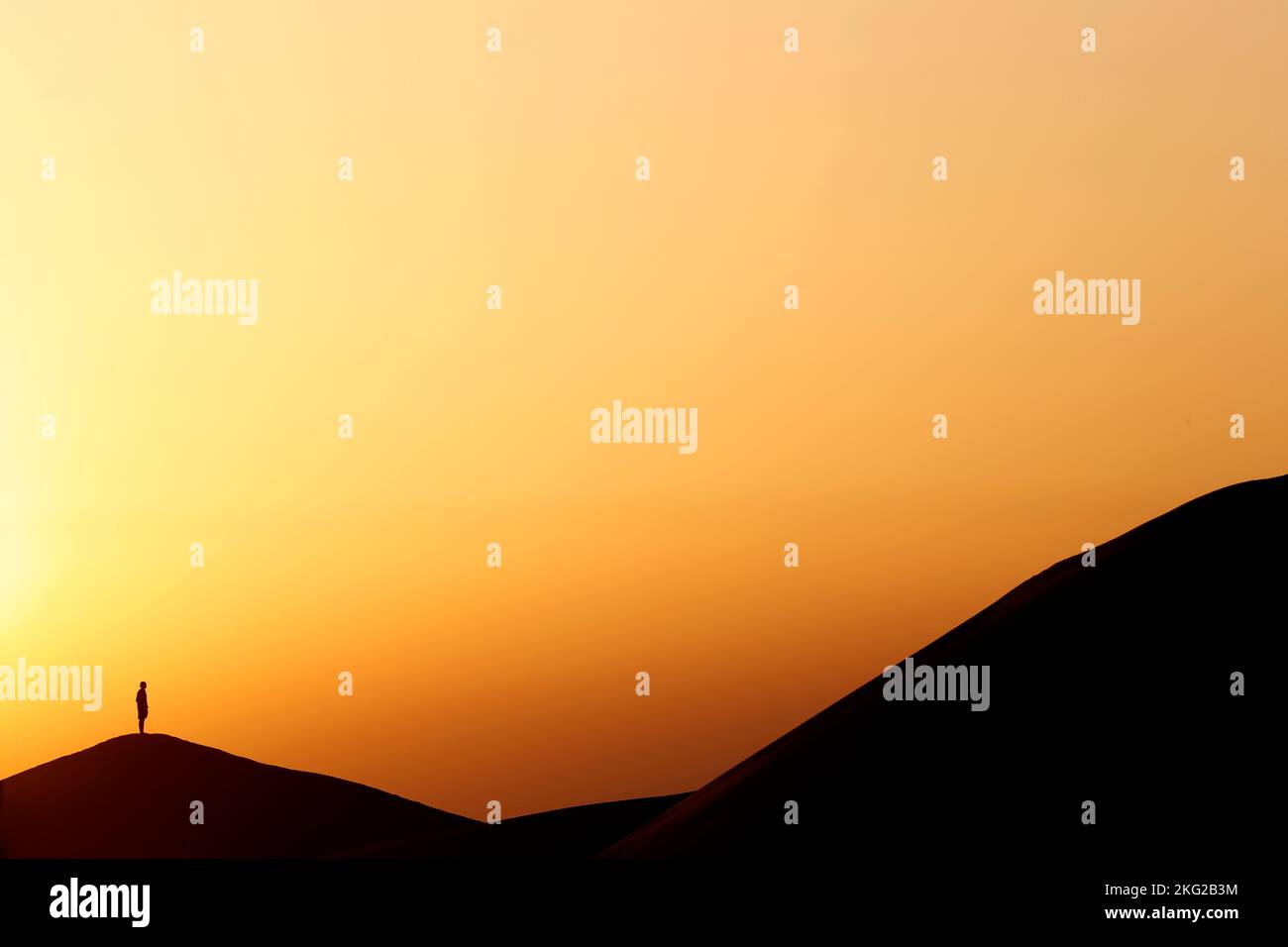 Silhouette auf Sanddüne. Meditation bei Sonnenuntergang in der Wüste. Konzept für Religion, Glauben, Gebet und Spiritualität. Stockfoto