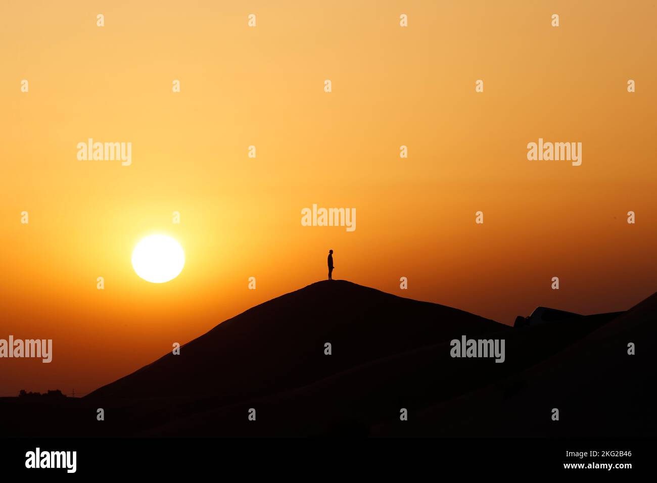 Silhouette auf Sanddüne. Meditation bei Sonnenuntergang in der Wüste. Konzept für Religion, Glauben, Gebet und Spiritualität. Stockfoto