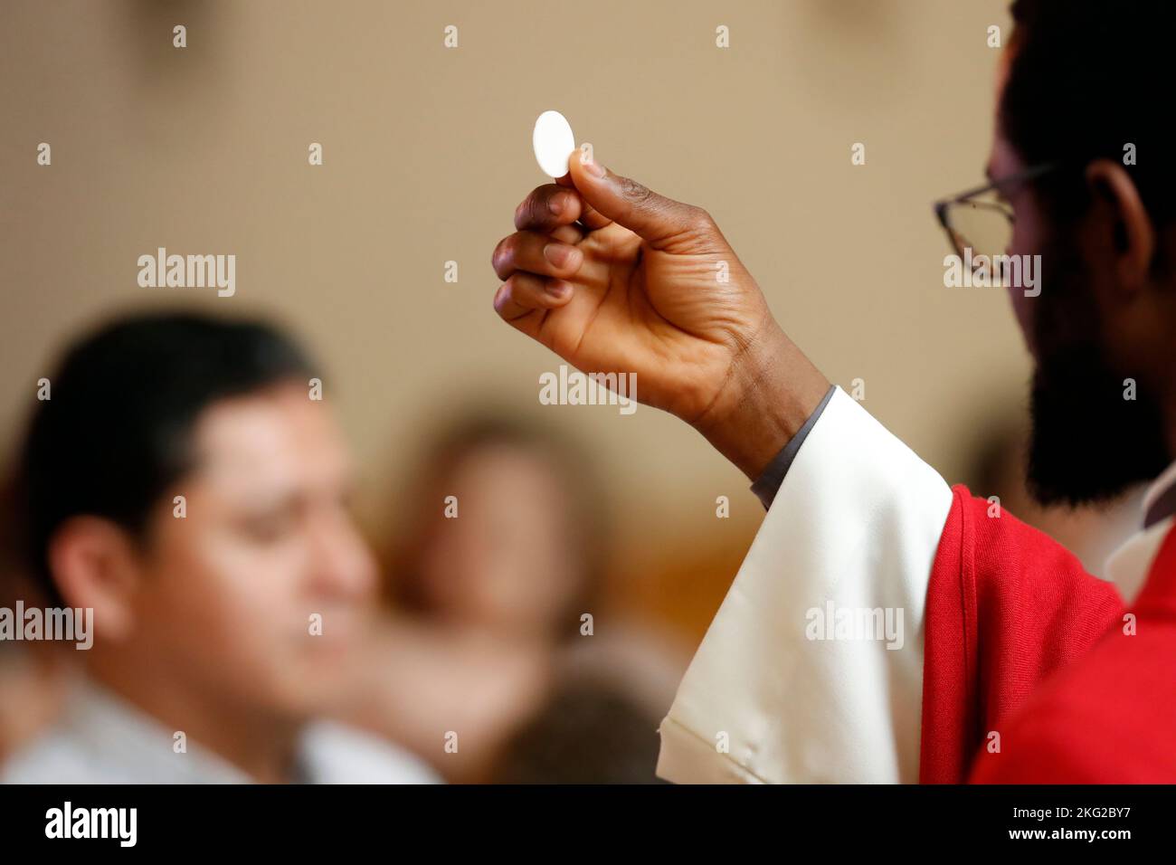 Sonntagsmesse in einer katholischen Pfarrei. Priester, der die heilige Kommunion gibt. Schweiz. Stockfoto