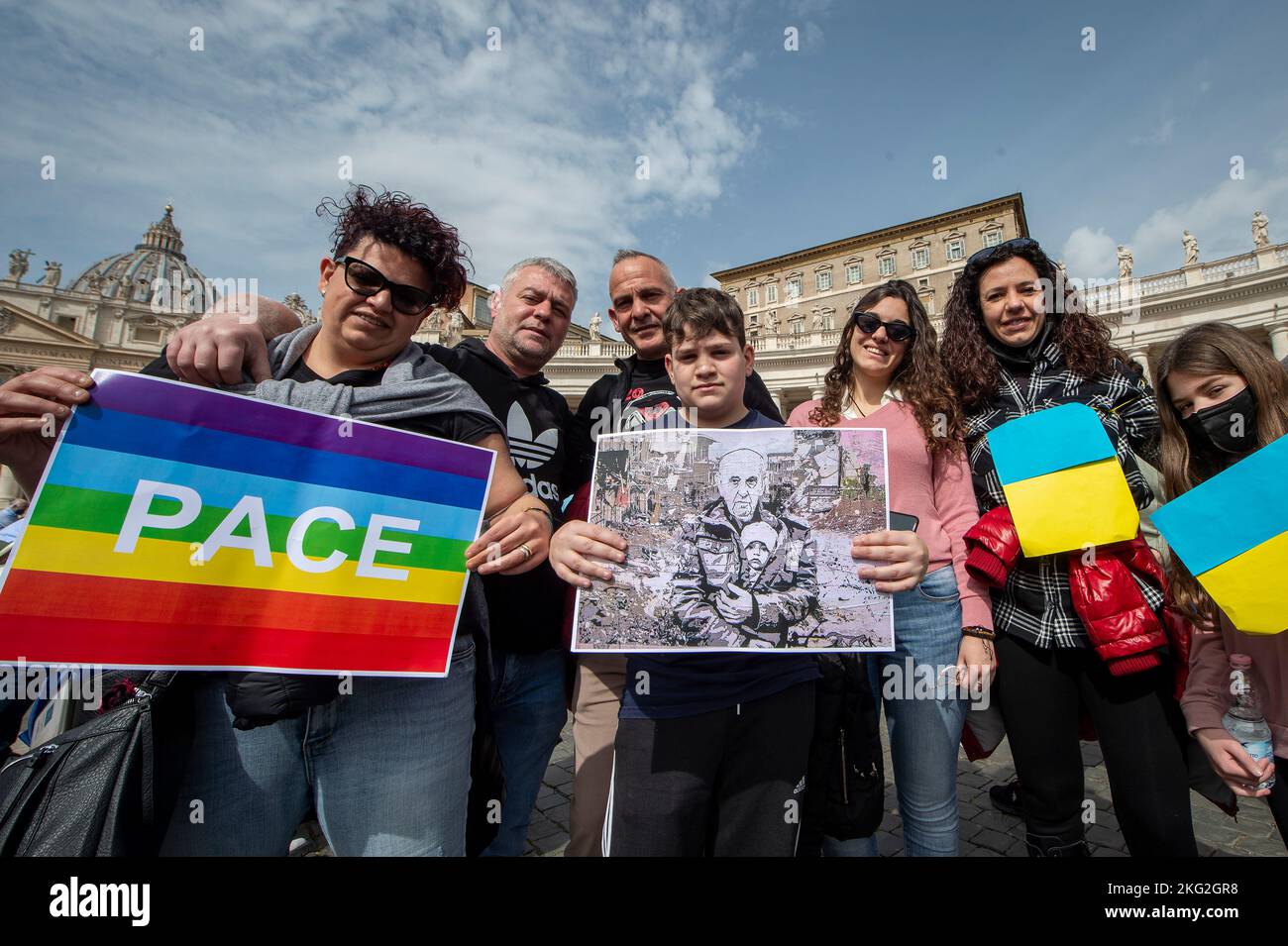 Eine ukrainische Familie hält eine Regenbogenfahne für den Frieden, eine ukrainische Flagge und eine Fotomontage von Papst Franziskus, der ein ukrainisches Kind beschützt, während Papst Fr. Stockfoto