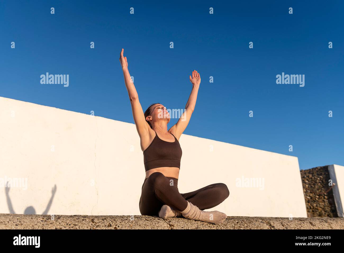 Sportliche Frau mit erhobenen Armen in den Himmel, genießen die Freiheit der Natur und Sonnenschein. Konzept von Wohlbefinden und gesunder Lebensweise Stockfoto