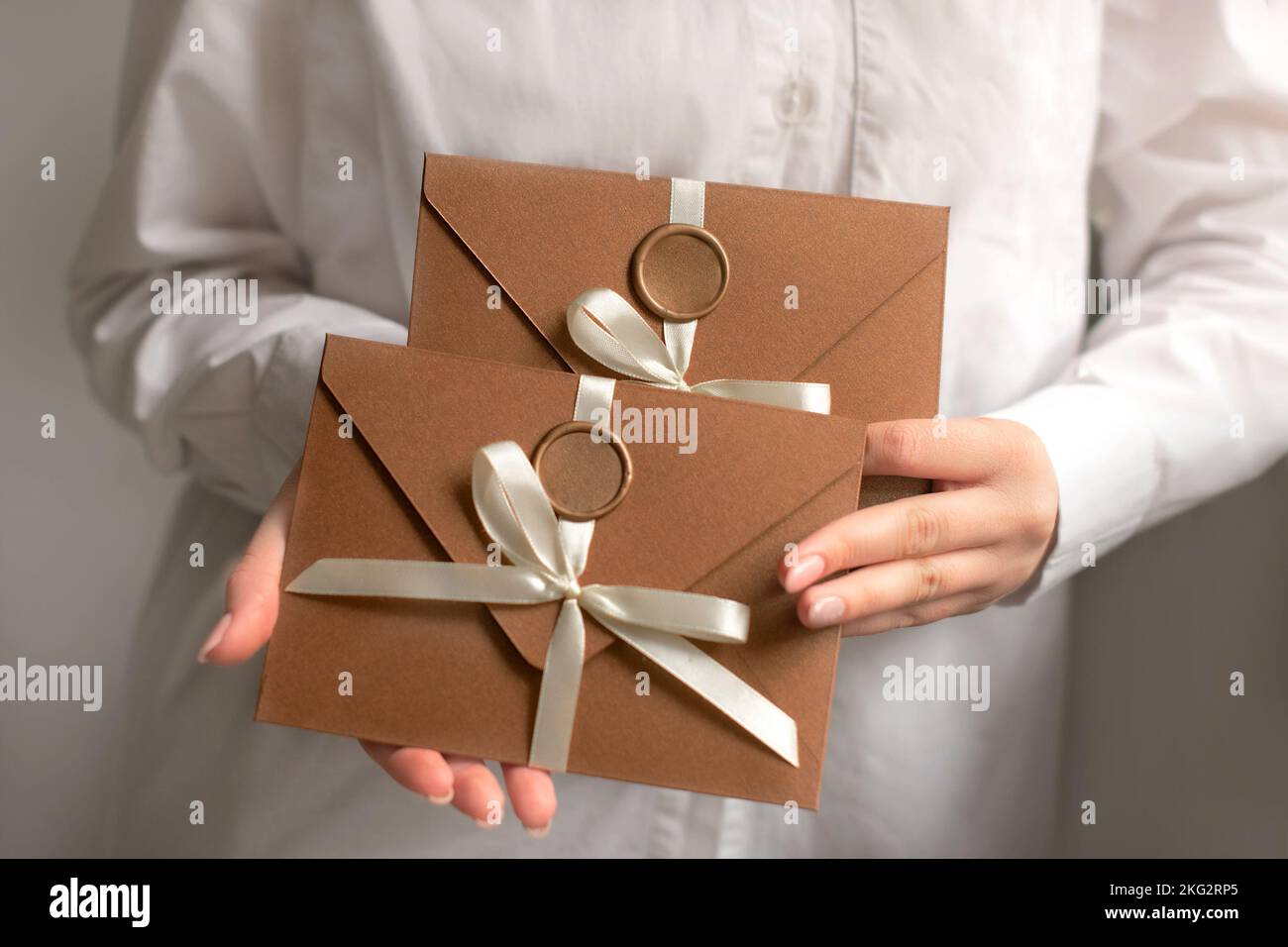 Handgefertigte Briefumschläge aus Bronze speichern die Datumskarten in Frauenhand. Der Geschenkgutschein ist das beste Geschenk Stockfoto