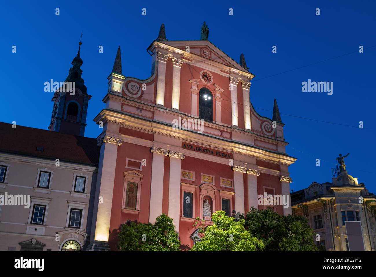 Die Franziskanerkirche der Verkündigung in der Nacht in Ljubljana, Slowenien. Beleuchtete Barockfassade aus dem Jahr 1703, Wahrzeichen der Stadt. Stockfoto
