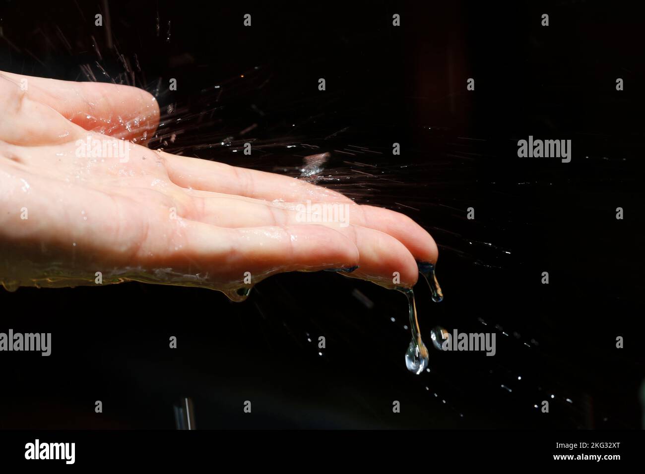 Nahaufnahme der Frauenhand im Regen. Regentropfen fallen ihr in die Hand. Regenzeit. Vietnam. Vietnam. Stockfoto