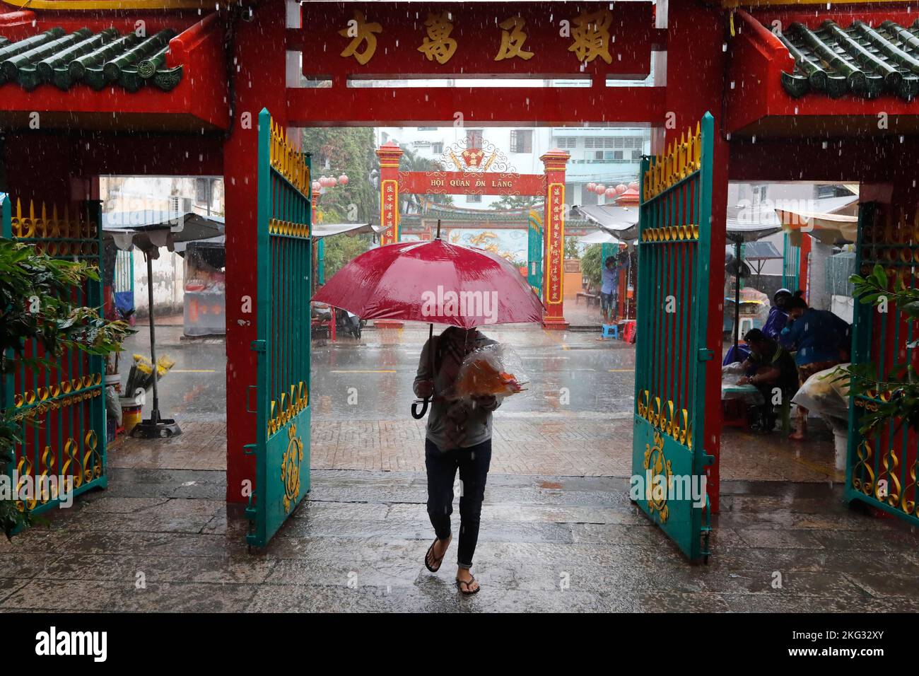 Quan am buddhistischer Tempel. Starker Regen während der Regenzeit. Mann mit Regenschirm. Ho-Chi-Minh-Stadt. Vietnam. Stockfoto