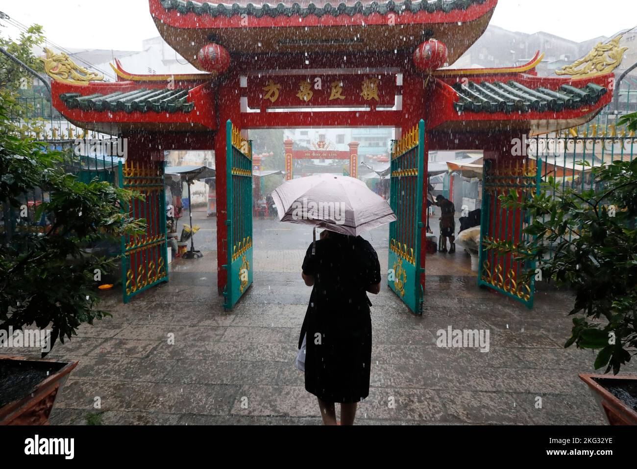 Quan am buddhistischer Tempel. Starker Regen während der Regenzeit. Frau mit Regenschirm. Ho-Chi-Minh-Stadt. Vietnam. Stockfoto