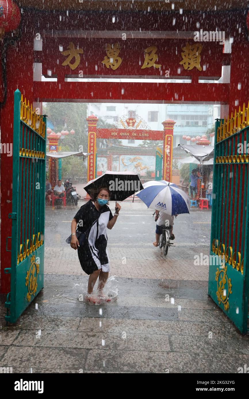 Quan am buddhistischer Tempel. Starker Regen während der Regenzeit. Frau mit Regenschirm springen im Wasser. Ho-Chi-Minh-Stadt. Vietnam. Stockfoto
