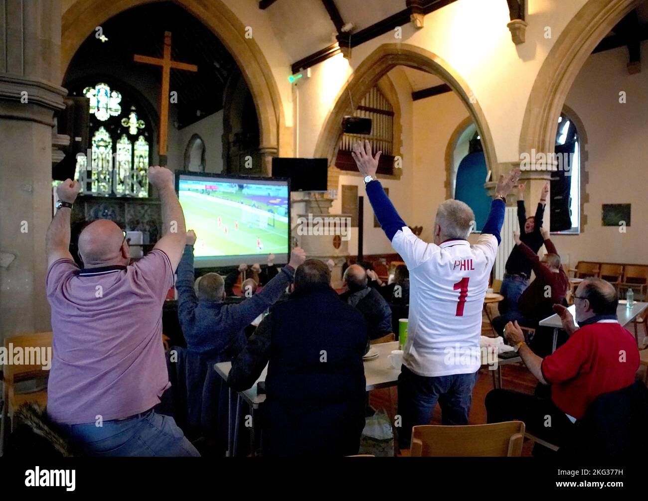 Die Fans feiern Englands drittes Tor, als sie das Spiel England gegen den Iran in der Holy Trinity Church in Sittingbourne, Kent, während der FIFA Weltmeisterschaft 2022 verfolgen. Bilddatum: Montag, 21. November 2022. Stockfoto