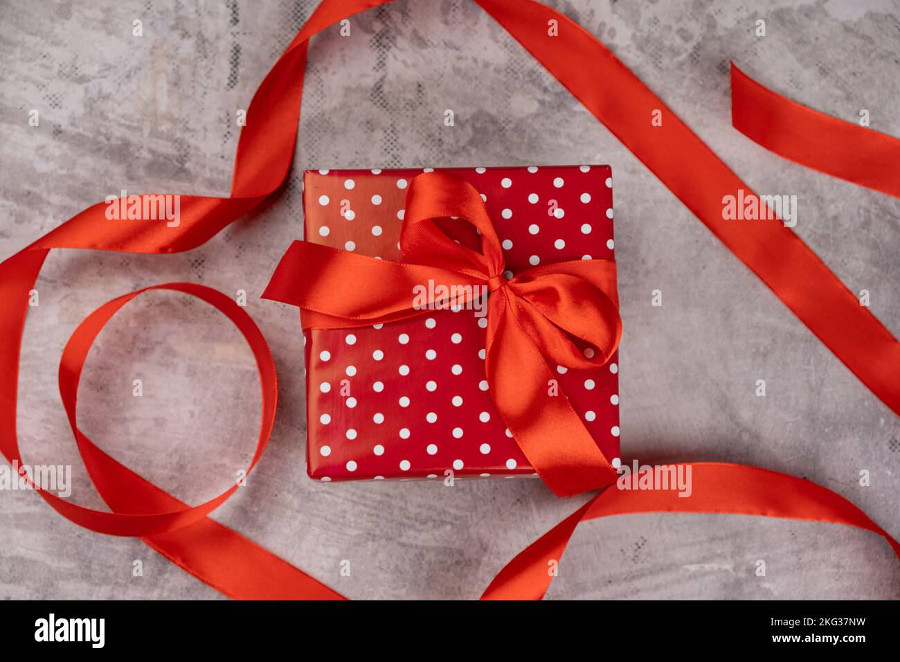 Geschenk und rotes Band auf grauem Hintergrund Stockfoto