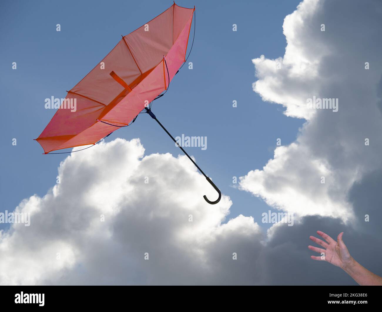 Die Hand der Frau mit dem Regenschirm in Windböen, der Himmel dahinter. Stockfoto