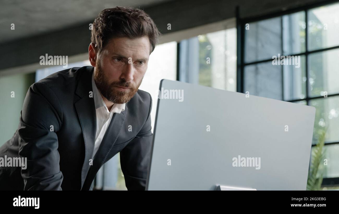 Kaukasisch beschäftigt bärtigen Mann Erwachsene 40s Geschäftsmann Arbeitgeber im Büro steht hat Problem mit Papierkram Eingabe von Daten Computer Online-Check-Bericht Stockfoto