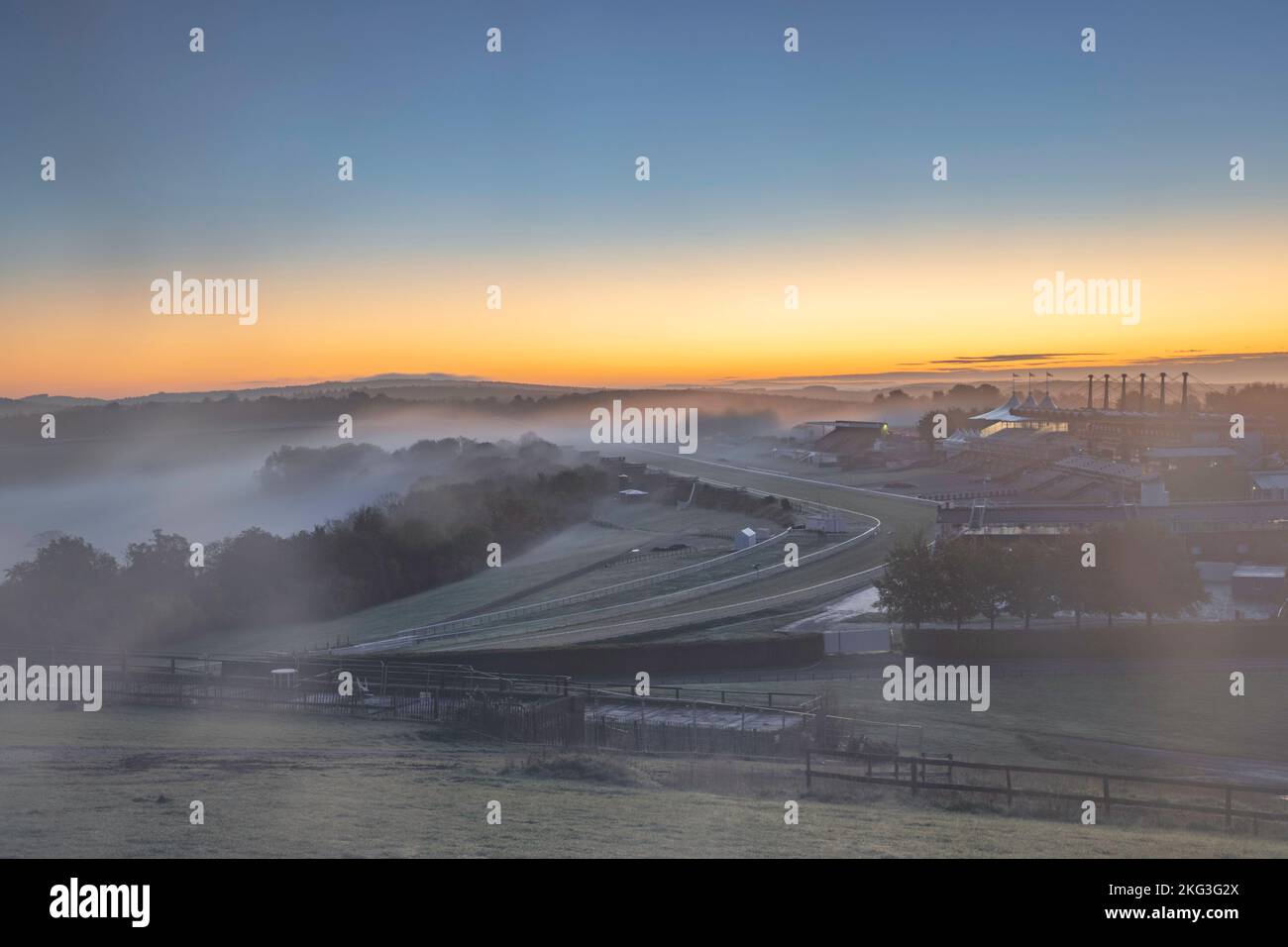 Die Rennbahn Goodwood im Morgengrauen mit einem sanften Nebel, der über die Rennbahn in der Nähe von Chichester, West Sussex, im South Downs National Park strömt. Stockfoto