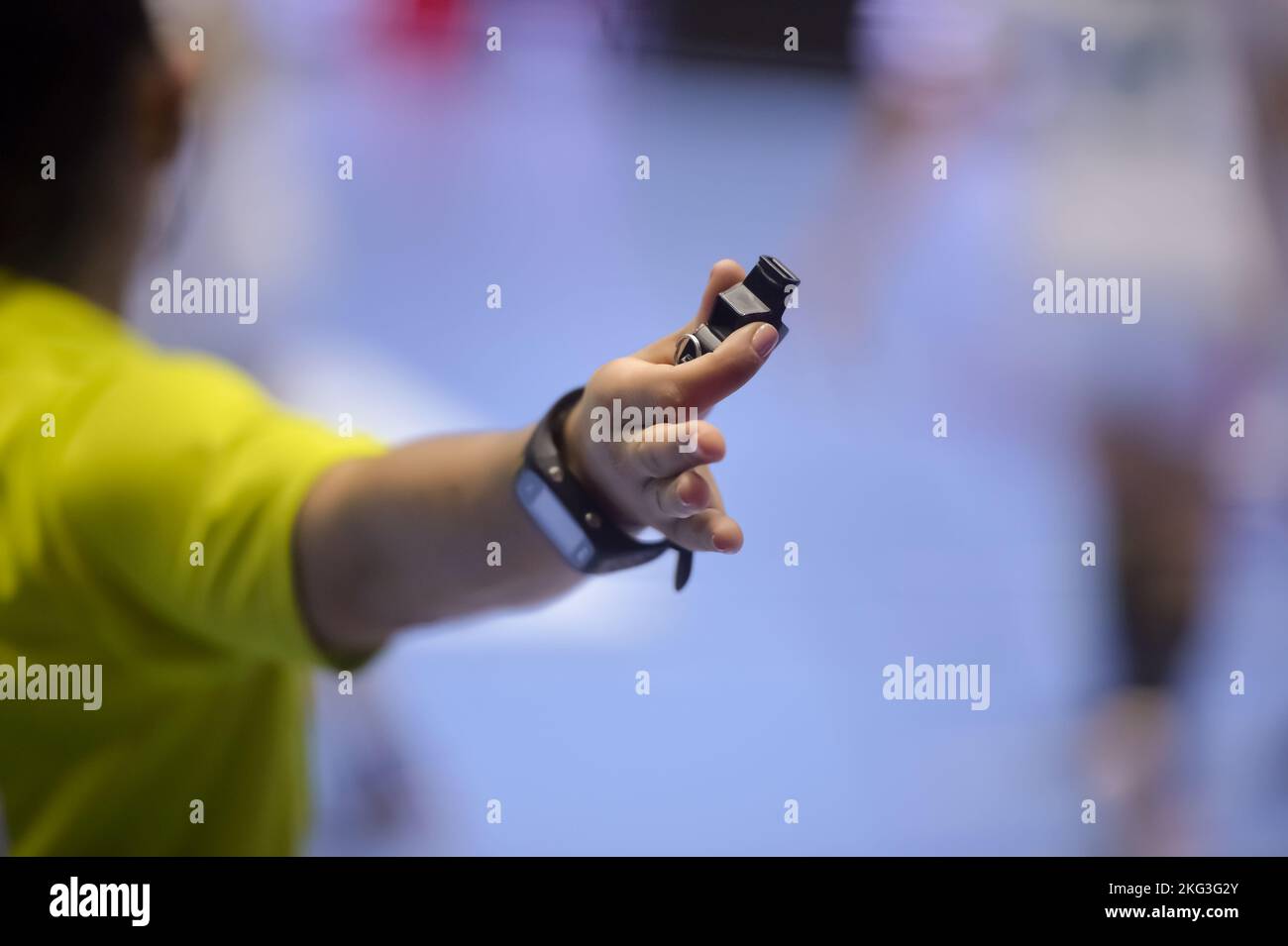 Geringe Schärfentiefe mit Handball-Schiedsrichterhand, die eine Pfeife hält, die ein Foul signalisiert Stockfoto