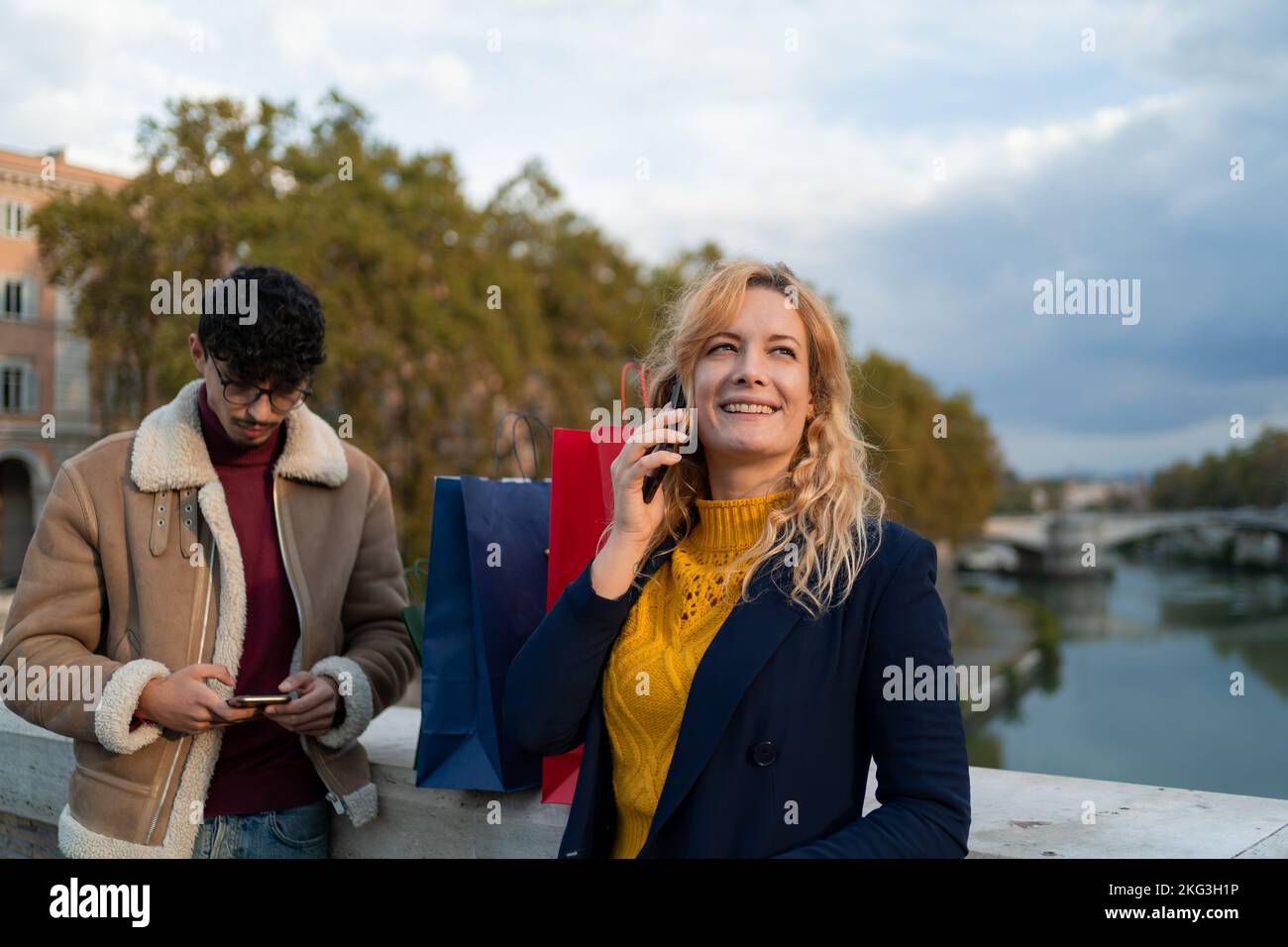 Selektiver Fokus auf blonde Frau, die nach dem Einkaufen mit ihrer Freundin über das Smartphone spricht Stockfoto