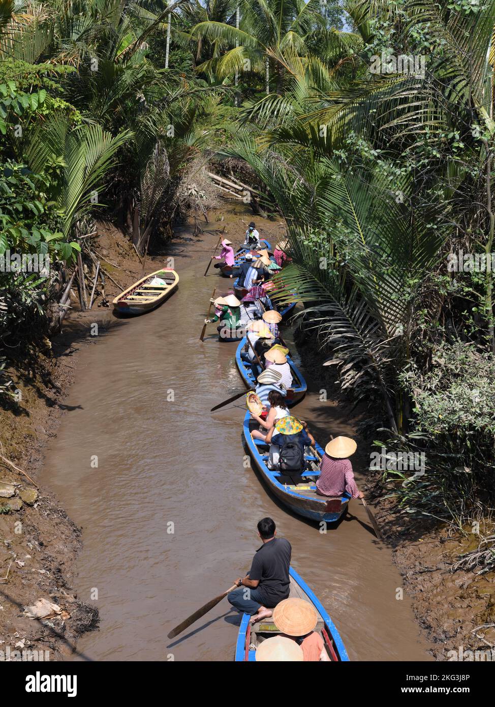 Touristen erkunden die engen Wasserwege und Nebenflüsse, die zum Mekong führen, mit traditionellen Kopfbedeckungen. Stockfoto