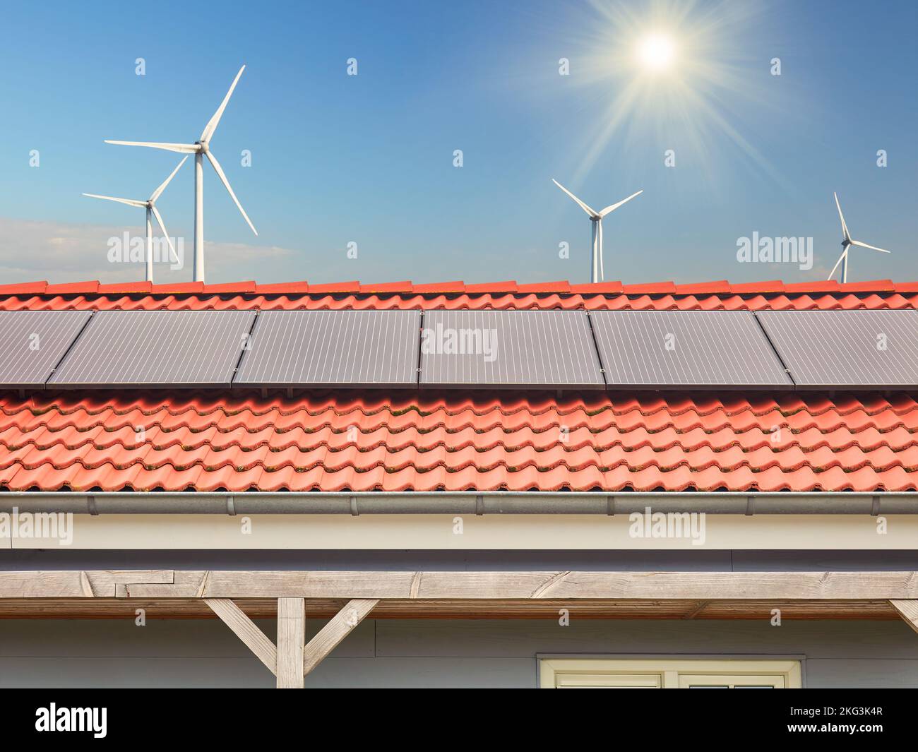 Dach eines holländischen Hauses mit Sonnenkollektoren vor Windturbinen und strahlender Sonne Stockfoto
