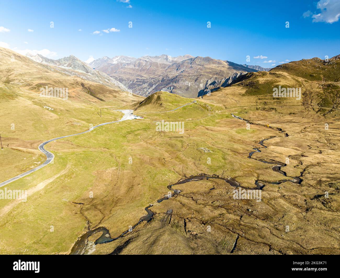 Aus der Vogelperspektive sehen Sie trockene Quellwege entlang der Straße, die von Grünland mit alpengebirgen in Europa umgeben sind Stockfoto