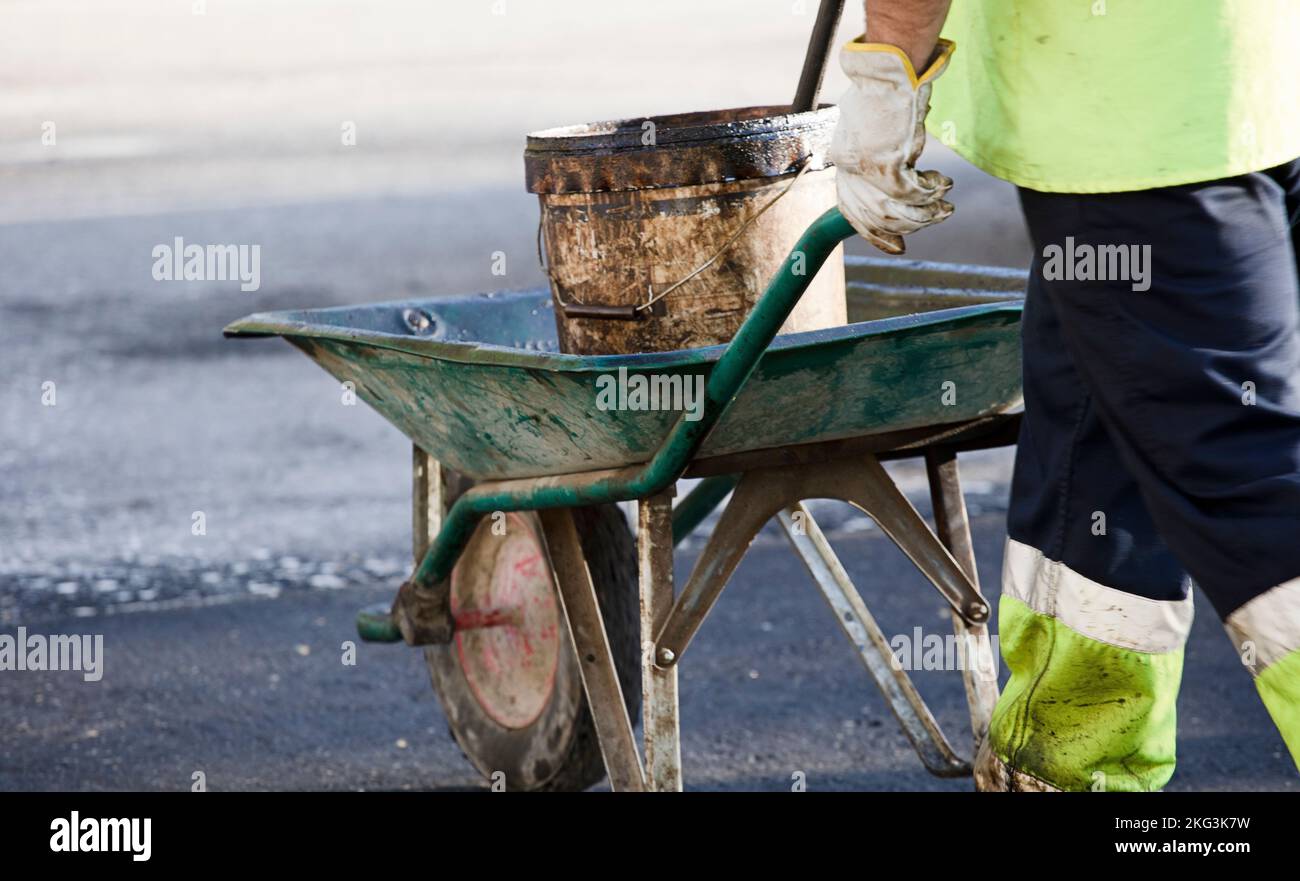 Handwagen mit Asphaltwerkzeugen, uniformierter Fahrer Stockfoto