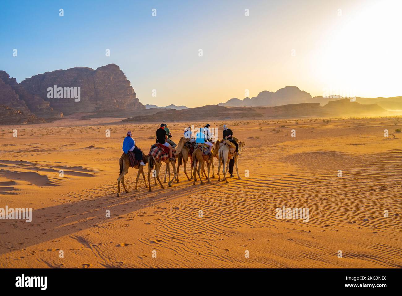 Touristen auf einem abendlichen Kamelpfad auf dem Sand des Wadi Rum Jordan Stockfoto