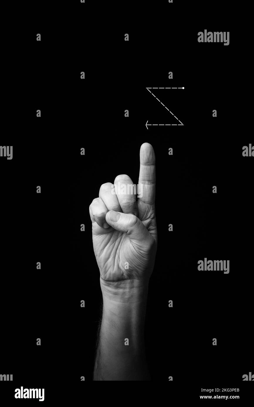 Dramatisches Schwarzweißbild eines männlichen Hands, das den Buchstaben „Z“ in der Zeichensprache Fench schreibt, isoliert vor einem dunklen Hintergrund mit Kopierraum Stockfoto