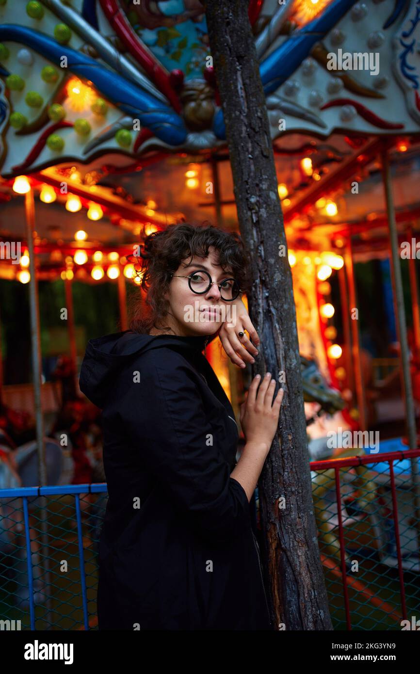 Eine lockige Frau, die neben dem Karussell steht Stockfoto