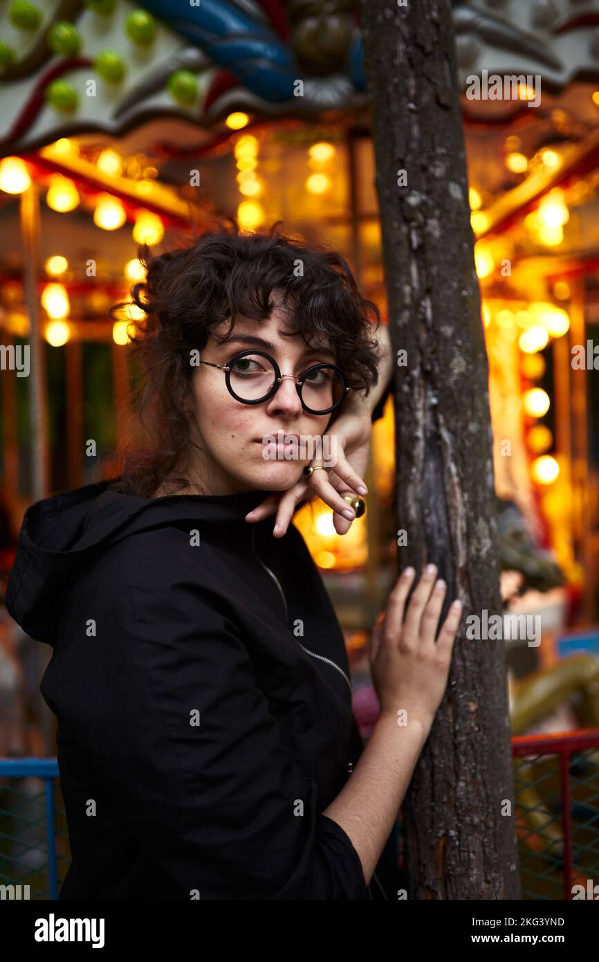 Eine lockige Frau, die neben dem Karussell steht Stockfoto