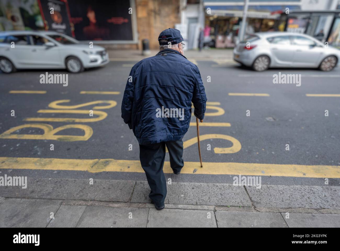 Ein alter Mann, der die Straßen von Kilburn mit einem Stock überquert Stockfoto