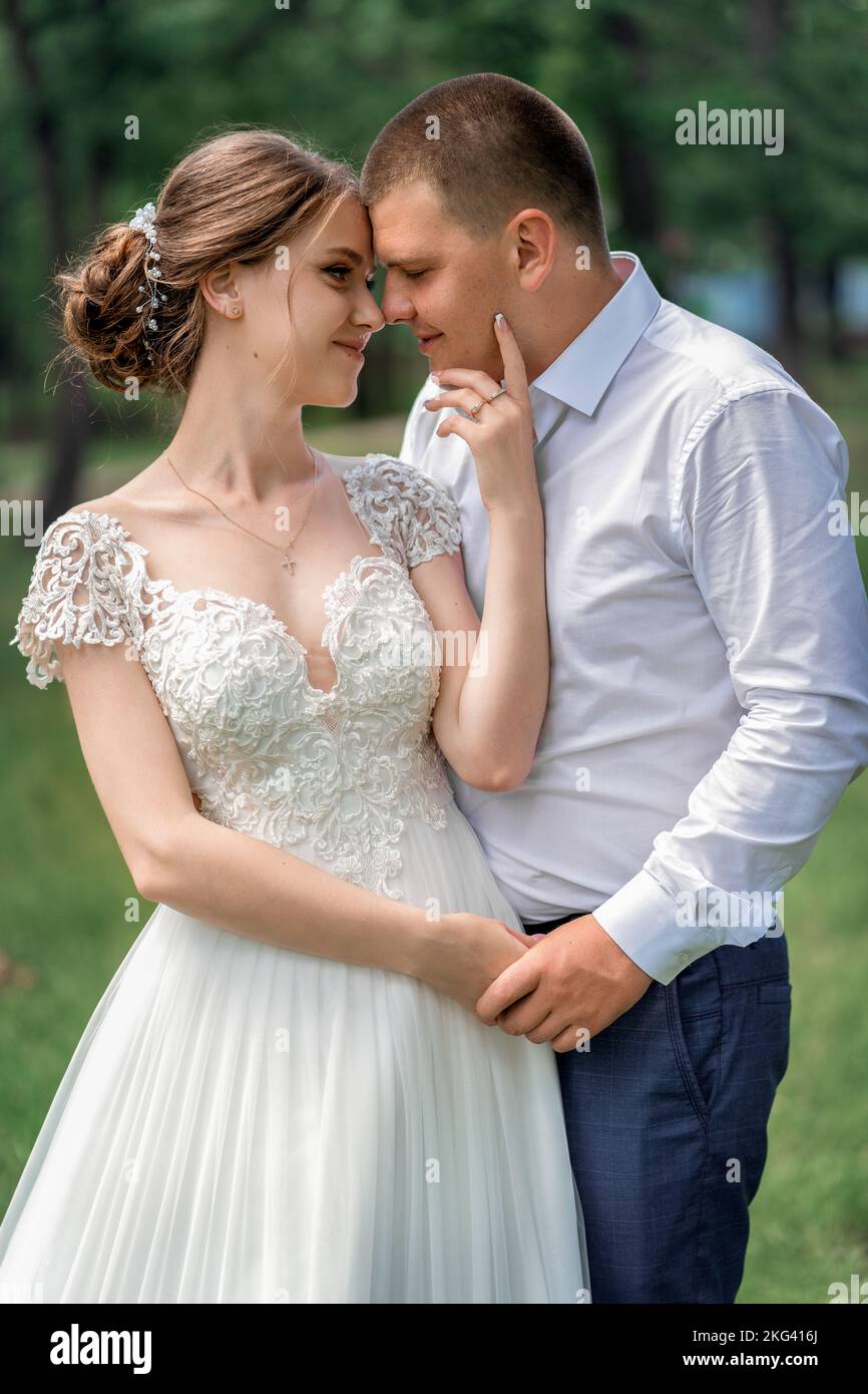 Die Braut hält sanft das Gesicht des Bräutigams Stockfoto