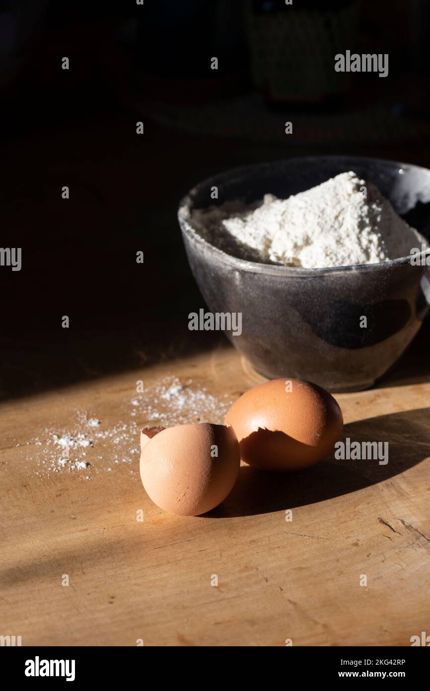 Zutaten für die Teigherstellung - Mehl in einer Schüssel, Eier. Hartes Licht Stockfoto