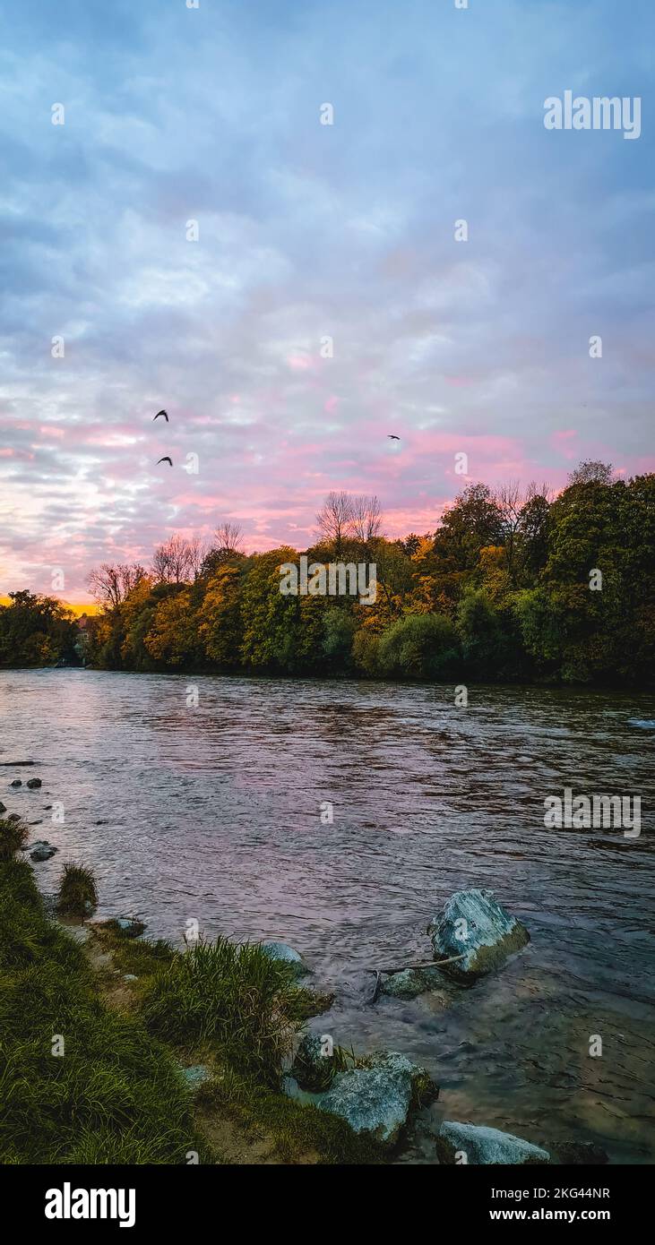 Eine vertikale Aufnahme der Münchener Isar bei Sonnenuntergang Stockfoto
