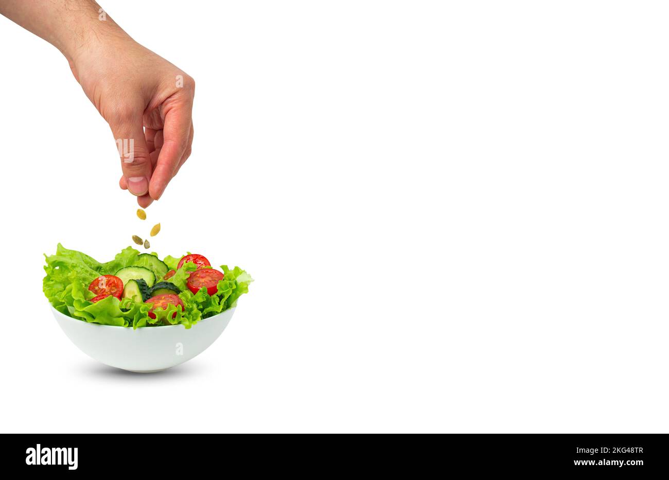 Schüssel Salat und männliche Hand bestreuen Samen über Salat isoliert Stockfoto