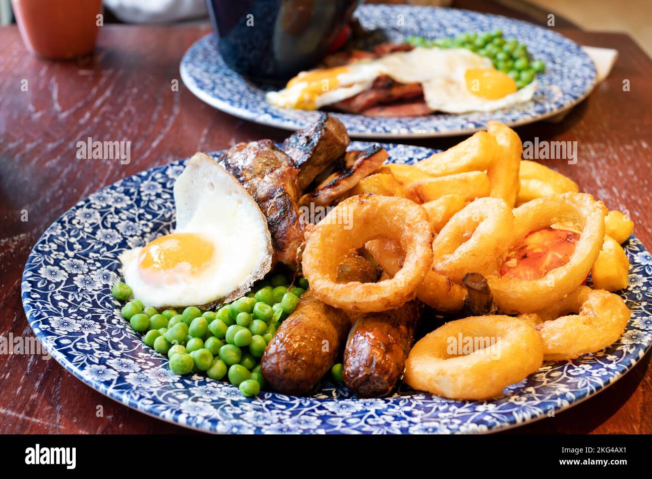 Ein JD Wetherspoons großes gemischtes Grillgericht mit Zwiebelringen und einem Spiegelei. Das preiswerte Essen ist auf einem Kneipentisch in einem Wetherspoons Pub Stockfoto