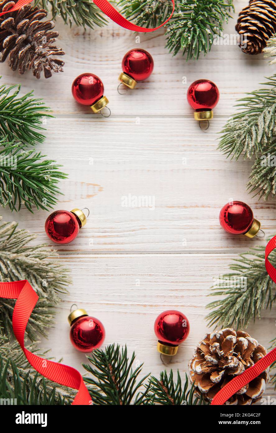 Weihnachtsdekoration mit rotem Band, das einen Rahmen auf einem weißen Holzhintergrund macht. Weihnachtsthemen. Flach liegend, Kopierplatz Stockfoto