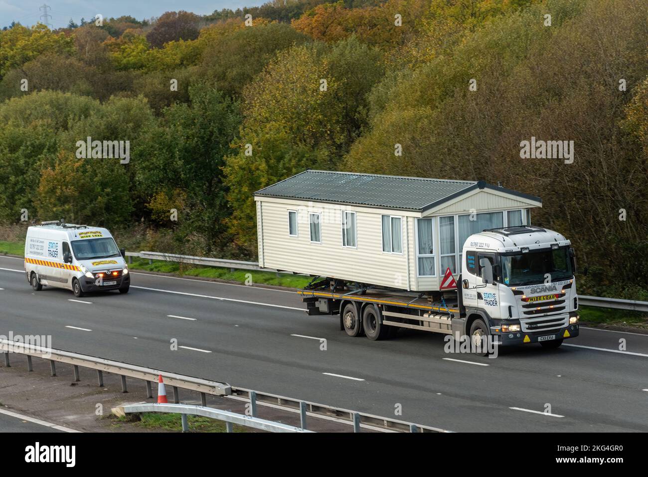 LKW-Transport eines Wohnmobils entlang der Autobahn M3, breite Ladung, England, Großbritannien, breite Ladung mit Begleitfahrzeug, das zurückfährt Stockfoto