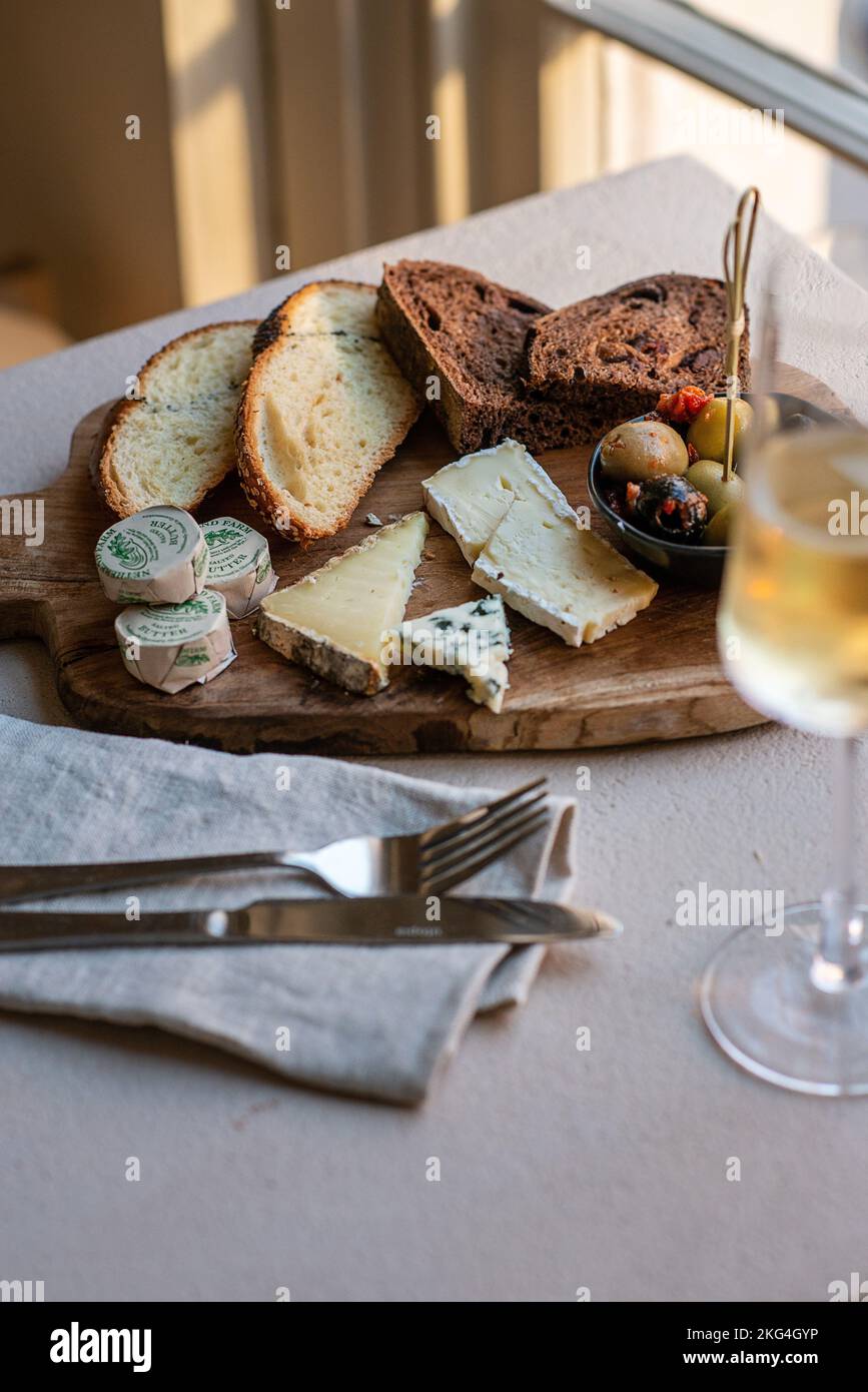 Eine vertikale Aufnahme von verschiedenen Käsesorten und Brot auf einem Holztablett Stockfoto