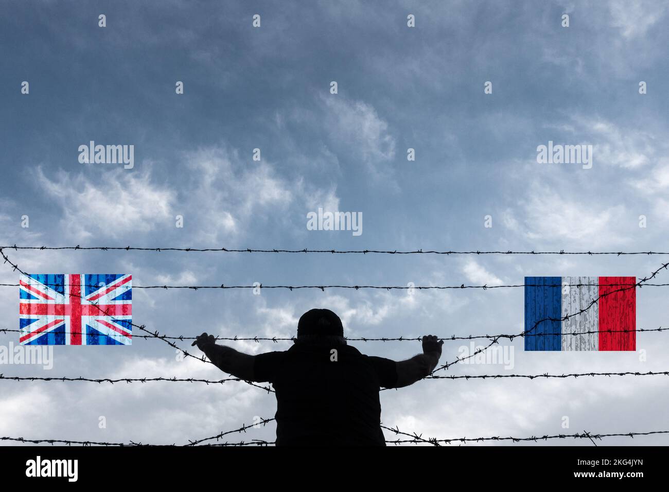 Mann, der durch Stacheldrahtzaun auf Strandfahnen von Großbritannien und Frankreich schaut. Grenzkontrolle, Kanalübertritt, Migranten, Asylbewerber, Einwanderung... Stockfoto