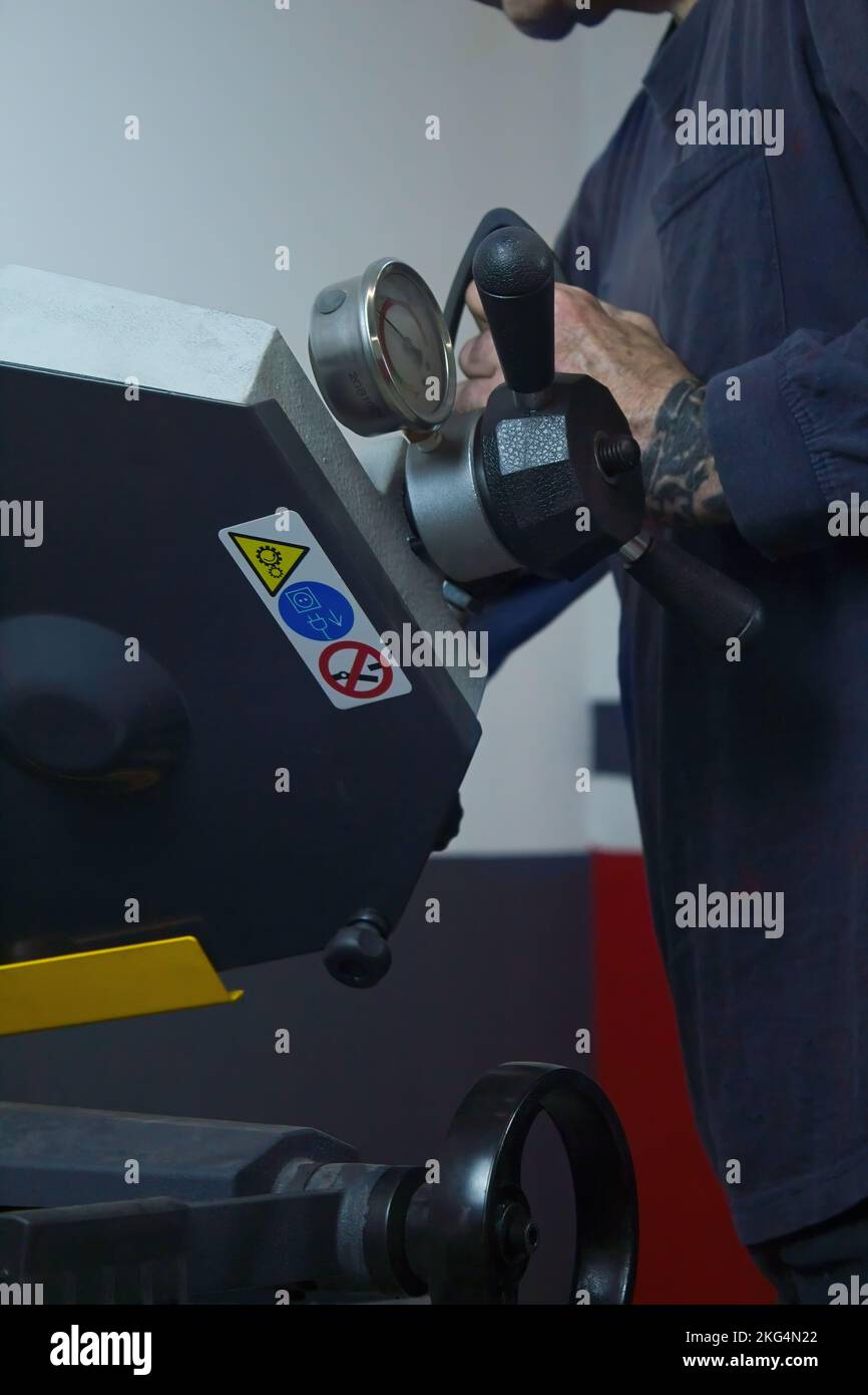 Nahaufnahme eines reifen Menschen, der mit einer Industriesäge in der Werkstatt Metall schneidet Stockfoto