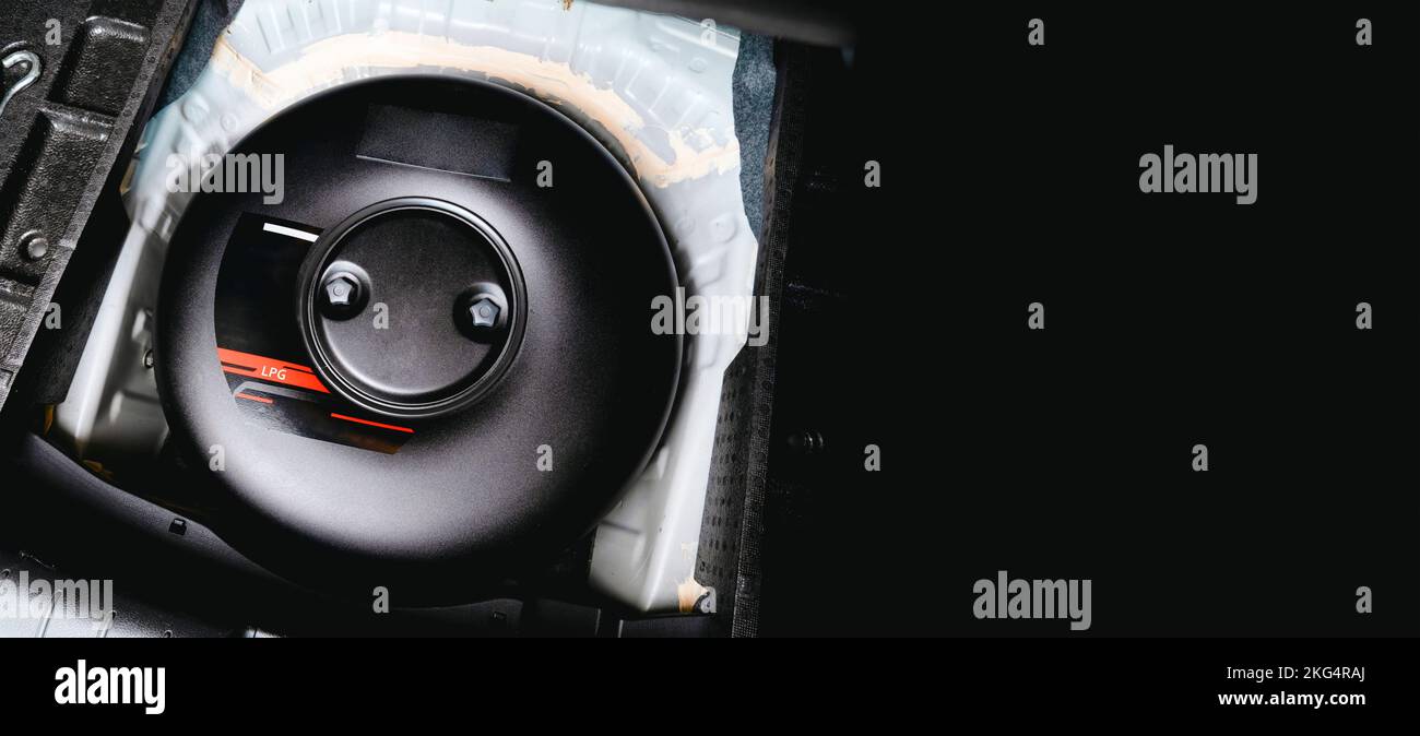 Schwarzer Treibgasbehälter in Form eines Donuts in einem Reserveradloch im Kofferraum eines Autos Stockfoto