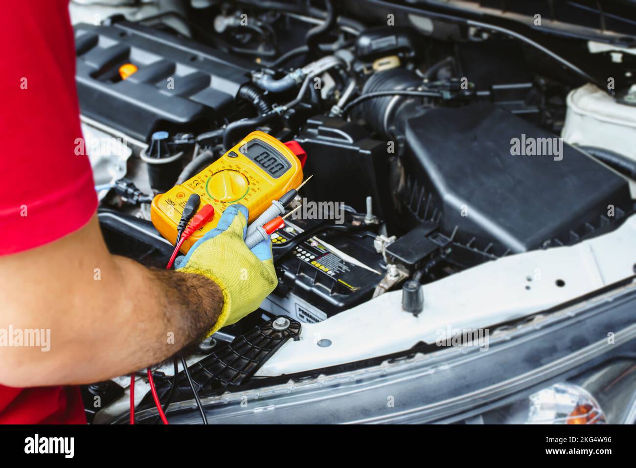 Ein Mechaniker hält ein Digitalmultimeter, um das elektrische System des Autos zu überprüfen, das Wartungskonzept für die Kfz-Wartung Stockfoto