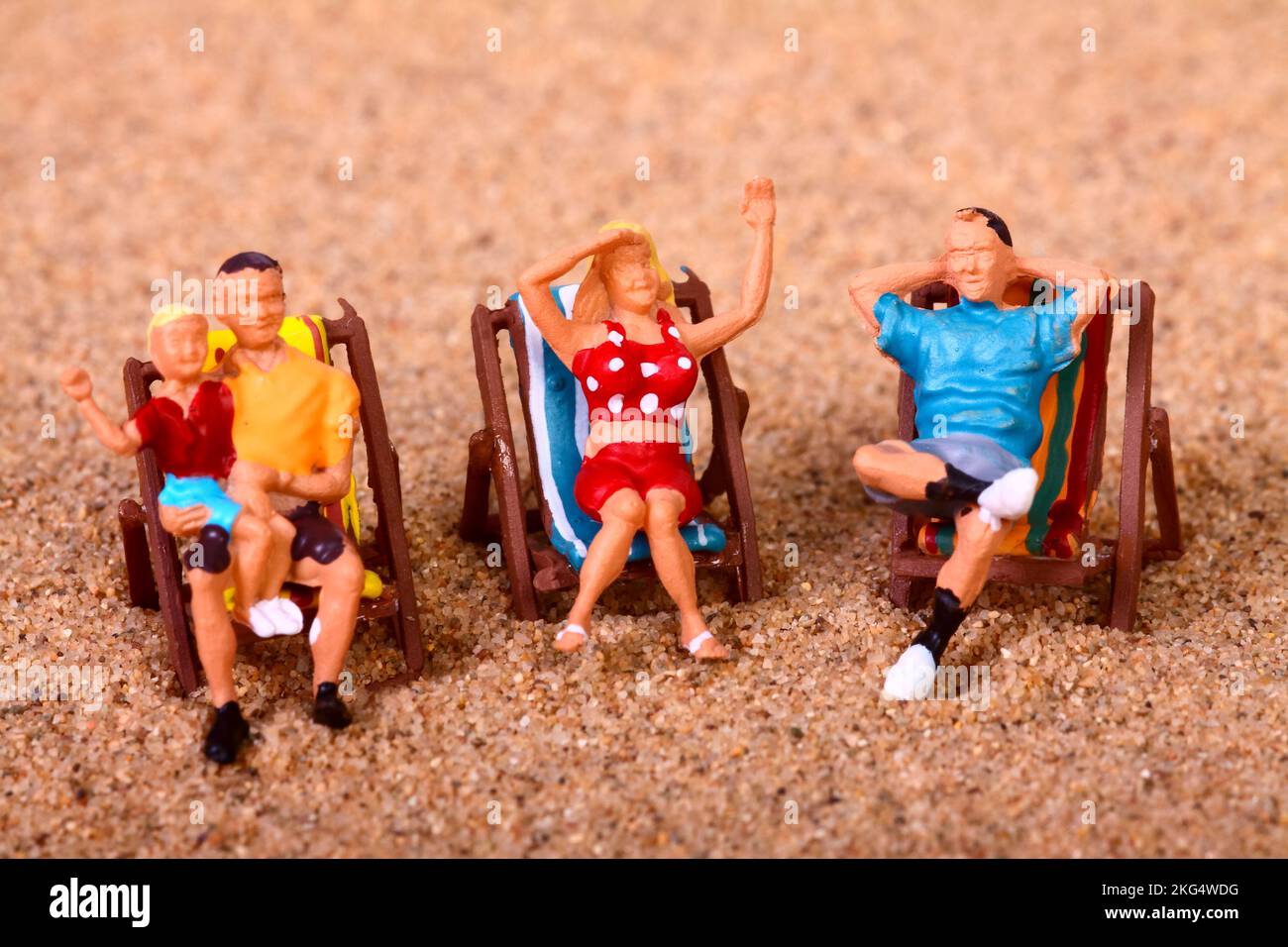 Konzeptionelles Bild einer Miniaturfigur, Leute saßen auf Liegestühlen an einem Sandstrand, Urlaubskonzept Stockfoto